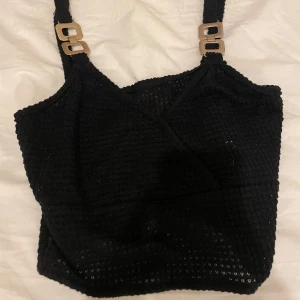 Svart ribbad linnetopp - Snygg svart ribbad linnetopp med guld detaljer vid axlarna 