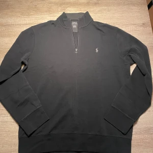 Svart tröja från Polo Ralph Lauren - Säljer en stilren svart tröja från Polo Ralph Lauren i storlek M. Tröjan har en dragkedja vid halsen och det klassiska Polo-logotypen broderad på bröstet. Perfekt för både vardag och lite finare tillfällen. Skön och enkel att matcha med det mesta i garderoben! Nypris 1500kr!!