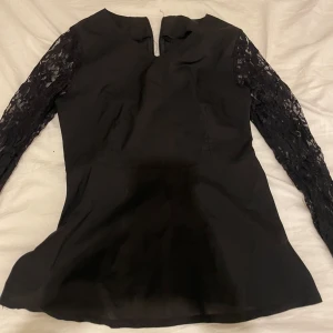 Svart blus  med spetsärmar - Svart elegant blus med spets armar och dragkedja i ryggen 
