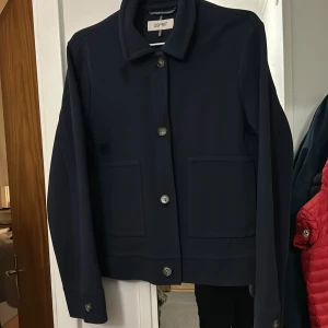 Mörkblå kavaj från Esprit - Snygg mörkblå kavaj från Esprit i mycket bra skick. Den har en klassisk design med knappar framtill och långa ärmar. Perfekt för höst och vår, och funkar både till vardags och fest. Storleken är inte angiven, men den ser ut att ha en normal passform.