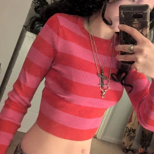 Röd och rosa randig tröja från Zara - Säljer en superfin röd och rosa randig tröja från Zara. Den är croppad och har en normal passform med långa ärmar. Skulle säga att den är storlek s bra skick 