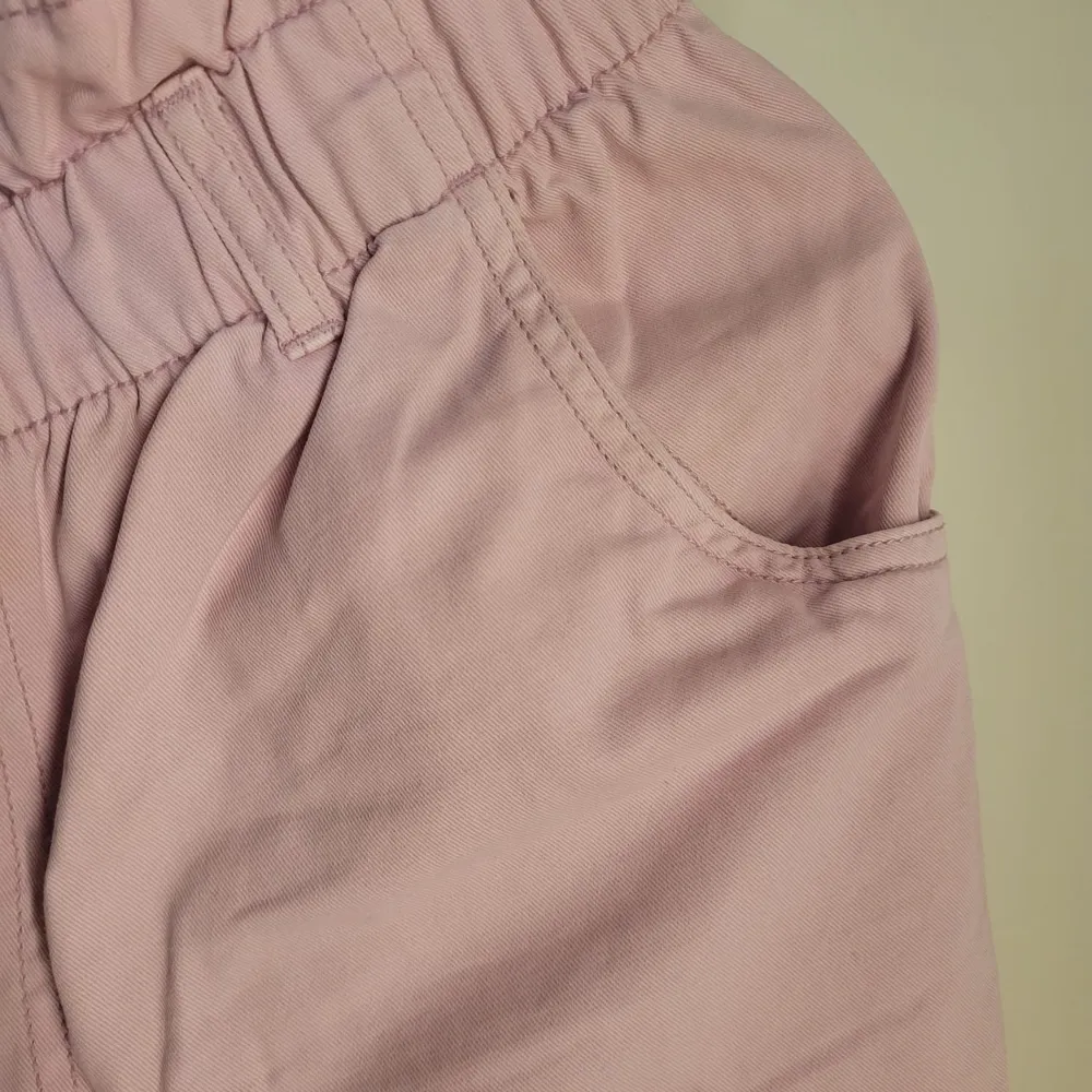 Säljer ett par ljusrosa shorts från H&M i storlek 40. De har en högmidjad design med elastisk midja och två knappar framtill. Perfekta för sommardagar med en avslappnad och bekväm passform. Materialet känns mjukt och luftigt, idealiskt för varma väder.. Shorts.