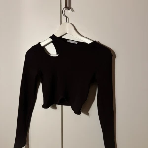 Svart ribbad topp från Gina Tricot - Säljer en svart ribbad topp från Gina Tricot. Den är croppad och har en unik offshoulder-design med långärmade ärmar. Perfekt för en stilren look till både vardag och fest. Passar bra till höst och vår.