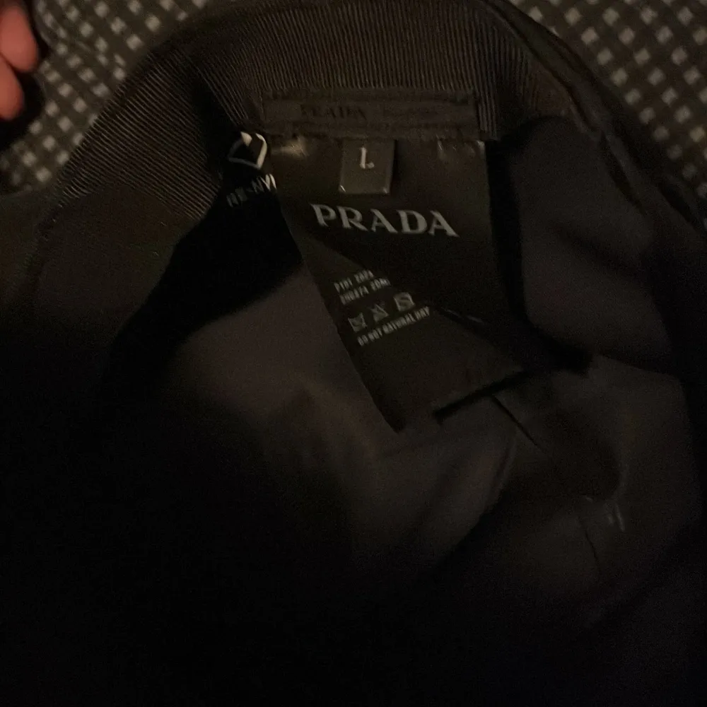 Säljer en stilren svart keps från Prada i storlek L. Kepsen har en klassisk design med Pradas logotyp i metall på framsidan. Perfekt för att ge din outfit en lyxig touch. Passar både till vardags och fest!. Accessoarer.