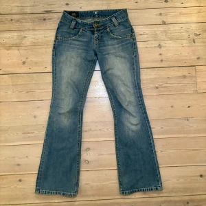 Blå bootcut jeans från Lee  - Säljer de här skitsnygga blåa lågmidjade bootcut jeansen från Lee, i storlek 25. Midjemåttet är 68 cm och innerbenslängden är 74 cm. Jeansen är bra kvalitet då de bara blivit använda fåtal gånger, lite nedtrampade på byxbenen men inget man märker vid användning. Säljer för att de inte kommer till användning. 