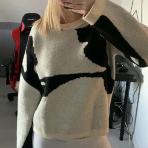 Beige och svart stickad tröja - Säljer en supermysig beige stickad tröja med coolt svart mönster. Perfekt för höst och vinter! Den har långa ärmar och en skön passform som är lite loose. Perfekt för att hålla sig varm och stilren samtidigt. 🖤🤍