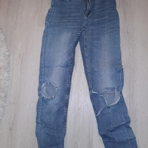 Blå jeans med slitningar - Säljer ett par blå jeans från 157 i bra skick. De har slitningar på knäna som ger en avslappnad look. Perfekta för vardagsbruk och passar till det mesta. De har en klassisk femficksdesign och är gjorda i ett bekvämt denimtyg!😊💞