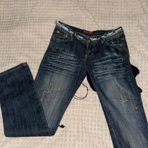 Blå jeans med slitningar - Säljer ett par snygga blå jeans med coola slitningar och en vintage look. Dem är lågmidjade: 36 cm rakt över inre benlängden: 80 cm. Skriv för mer info. Kan gå ner i pris
