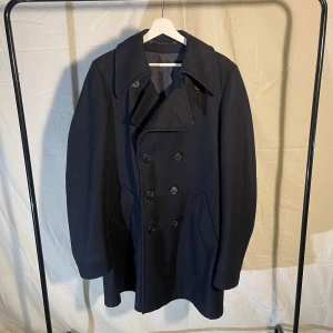 Peacoat  - Marinblå Peacoat i ull från märket Luxa d’or | i bra skick | Mått: Bred över axlar Ca 47cm, Midjemått bredd cirka 50 cm, bredd längst ner ca 62cm, Längd ca 90cm, armlängd ca 68cm. | 