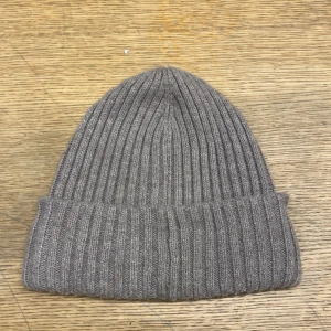 Beige ribbad mössa från H&M - Säljer en snygg beige ribbad mössa från H&M. Perfekt för kyliga dagar med sin mjuka och bekväma passform. Tillverkad i en blandning av polyester och akryl, vilket gör den både varm och hållbar. Passar till alla dina vinteroutfits!