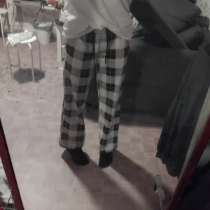 Pyjamasbyxor  - Säljer ett par svartvita rutiga Pyjamasbyxor i loose fit. Perfekta för en avslappnad stil eller mysiga hemmakvällar. Byxorna har en bekväm passform och är gjorda i ett mjukt material. De är i bra skick och redo för en ny ägare!