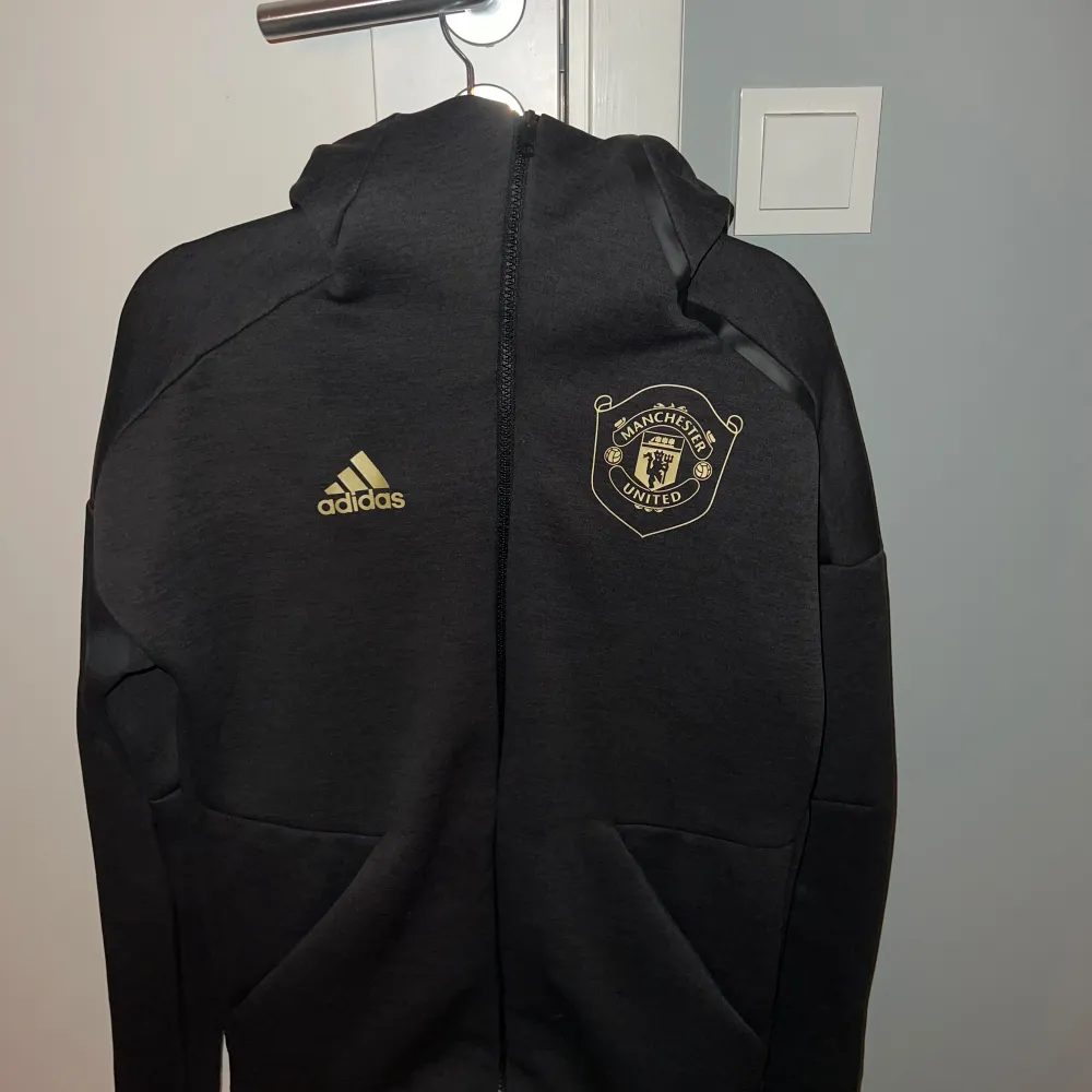 Säljer en svart hoodie från Adidas med Manchester United-logga. Detta var en limited edition som bara gick att få tag på under en kort period. Ny pris på denna ligger på 1500kr, mitt pris 495kr!! Hör av er för fler bilder eller funderingar!😄. Hoodies.