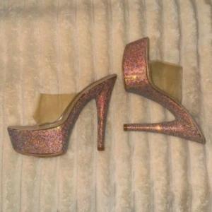 Glittriga klackskor från Fashion Nova - Säljer ett par superglittriga klackskor från Fashion Nova. De har en transparent rem över foten och en hög klack som verkligen sticker ut. Perfekta för en festkväll när du vill glänsa! Skorna är i mycket bra skick och redo att användas. använda 2 gånger