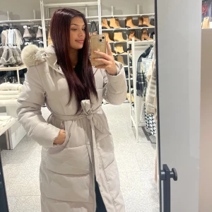 Beige parkajacka med pälsdetalj - Säljer en supermysig beige parkajacka med pälsdetalj på huvan. Jackan har en knytning i midjan och långa ärmar, perfekt för kalla vinterdagar. Den är i mycket bra skick och passar perfekt för både vardag och festliga tillfällen. Storlek S. TRUE 2 SIZE. Jag är 158 cm och jackan går över knäna.  Vill man ha pälsen kostar de 100 kr extra😊