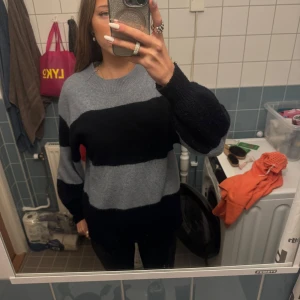 Randig stickad tröja från H&M - Säljer en mysig stickad tröja från H&M i grått och svart. Den har ett randigt mönster och långa ärmar, perfekt för kyliga dagar. Tröjan är i bra skick och passar både till vardags och lite mer avslappnade tillfällen.