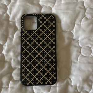 Svart och  beige mobilskal från By Malene Birger - Snyggt mobilskal från By Malene Birger i svart med beige geometriskt mönster. Perfekt för att ge din mobil en stilren look samtidigt som den skyddas. Passar perfekt för vardagsbruk eller när du vill ha en extra touch av stil.