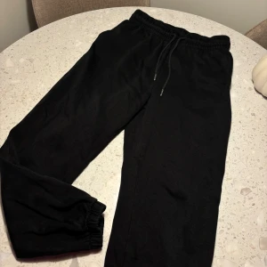 Svarta mjukisbyxor från H&M - Säljer ett par svarta mjukisbyxor från H&M i storlek M. De är superbekväma med resår och snörning i midjan, perfekt för en chill dag hemma eller en snabb tur till affären. Byxorna har en loose passform och är gjorda i mjukt material. Ett måste för garderoben!