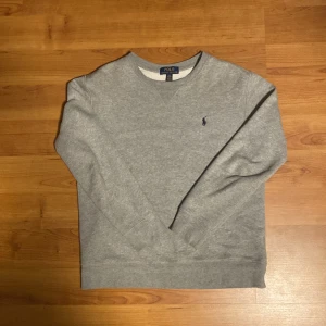 Grå tröja från Polo Ralph Lauren - Säljer en stilren grå tröja från Polo Ralph Lauren i storlek L barn storlek vilket motsvarar ungefär XS (passar bäst runt 165) Tröjan har en klassisk design med långärmade ärmar och en liten broderad logga på bröstet. Skick 7,5/10 lite smutsfläckar men går bort hur enkelt som helst i tvätten! Skriv vid intresse! ✌🏼💯