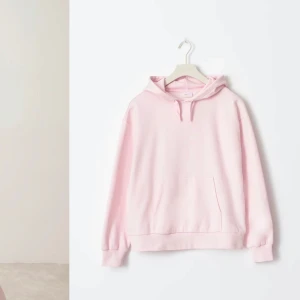 Ljusrosa hoodie - Säljer en supermysig ljusrosa hoodie i mycket bra skick. Perfekt för kyliga dagar eller bara för att chilla hemma. Den har en klassisk känguruficka och en skön huva med dragsko. Passar perfekt till jeans eller leggings. 🩷aldrig använd!! 