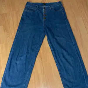 Säljer ett par snygga blå jeans från Lee i mycket bra skick. Modellen är wide leg. Jeansen har knappar framtill och är perfekta för både vardag och fest!