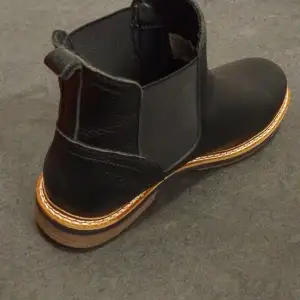 Snygga svarta Chelsea boots i skinn från Björn Borg. De har en klassisk design med elastiska paneler på sidorna och en robust sula i trälook. Perfekta för både höst och vinter, dessa boots är både stiliga och praktiska. Passar till både vardag och lite finare tillfällen.