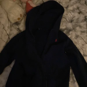Mörkblå hoodie från Polo Ralph Lauren - Säljer en snygg mörkblå hoodie från Polo Ralph Lauren. Den har en klassisk design med det röda logotypen på bröstet🥰. Hoodien är i bra skick och redo för nya äventyr! Säljer pågrund av att den tyvär är lite för liten för mig men annars så är den jätte fin!❤️