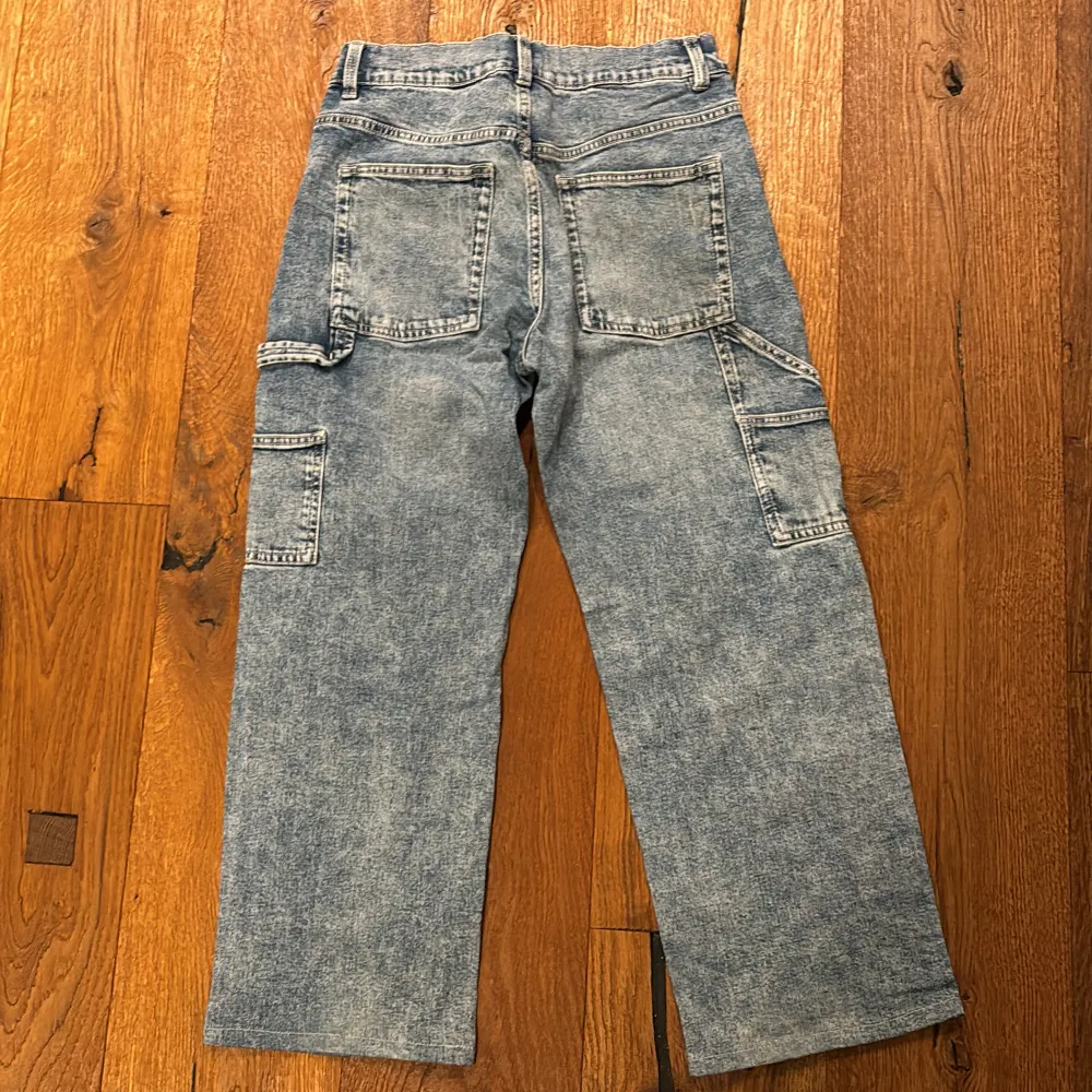 Säljer ett par snygga blå jeansbyxor från Lindex i storlek 158. De har en klassisk femficksdesign med extra fickor på sidorna, perfekt för en casual look. Byxorna är i bra skick och har en bekväm passform. Perfekta för både vardag och skola!. Jeans & Byxor.