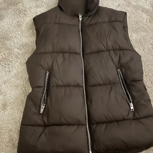 Grön jacka med svarta skinnärmar strl M & en brun dunväst från veromoda strl M  - Säljer en cool grön jacka med svarta skinnärmar. Jackan har en asymmetrisk dragkedja och flera fickor med dragkedjor. Perfekt för höst och vår när du vill ha en edgy look. Passar bra till både jeans och kjol! Aldrig använd & dunväst använd vid två tillfällen 