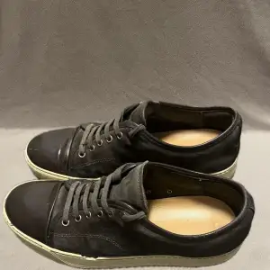 Säljer ett par svarta sneakers från Lanvin i bra skick. Skorna har en stilren design med snörning och en vit sula som ger en snygg kontrast. Perfekta för både vardag och fest. Passar till det mesta i garderoben!