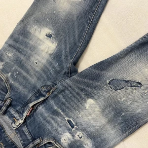  Dsquared2 jeans - Säljer ett par äkta dsquared2 jeans med riktigt snygga slitningar. Perfekta för grisch stilen. De har en klassisk femficksdesign och knappgylf. Passar perfekt till både vardag och fest. Sitter perfekt, slim fit. Har kvitto på dom som bevis på att dom är äkta! Kan gå ner i pris vid snappaffär!