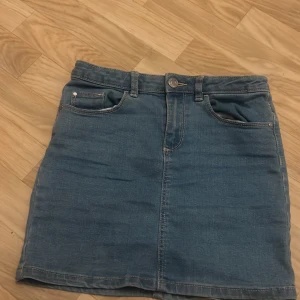Blå jeanskjol från Cubus - Säljer en snygg blå jeanskjol från Cubus i storlek 146/152. Kjolen har en klassisk femficksdesign och är perfekt för vardagsbruk. Materialet är en blandning av bomull och polyester, vilket gör den både bekväm och hållbar. Perfekt för vår och sommar! 🌼👖