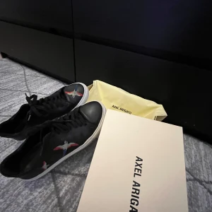 Axel Arigato Clean 90 Bee Birds Black - Säljer ett par snygga svarta sneakers från Axel Arigato i skinn. De har broderade fåglar på sidorna. Pris kan diskuteras vid snabbt köp!!
