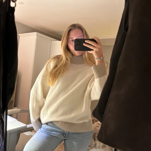 Vit oversized polotröja - Säljer en supermysig vit polotröja med beiga ribbade detaljer vid krage, ärmslut och nederkant. Perfekt nu för hösten. Tröjan har en oversized passform. Passar perfekt till jeans eller leggings. Säljer för att den inte kommer till användning längre. Den är i otroligt bra skick!💗