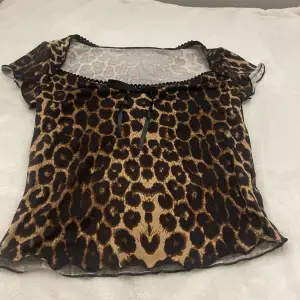 Säljer en snygg leopardmönstrad topp i mycket bra skick. Den har korta ärmar och en söt liten rosett framtill. Perfekt för en utekväll eller fest! 🐆✨