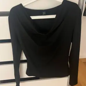 Snygg svart långärmad topp från Zara i ett mjukt och stretchigt material. Den har en elegant draperad halsringning som ger en stilren look. Perfekt för både vardag och festliga tillfällen. Passar bra till både jeans och kjol!