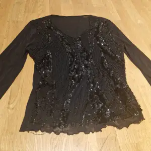 Säljer en svart glittrig mesh topp med långa ärmar och v-ringning. Toppen har paljettdetaljer som ger en festlig look. Perfekt för en utekväll eller nyår! 🖤✨ 