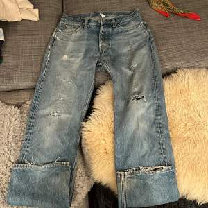 Säljer ett par blå Weekday jeans i relaxed straight fit. De har en cool slitning och knappar i gylfen. Perfekta för en avslappnad stil. Passar bra till allt slitheten lägger sista touchen! 