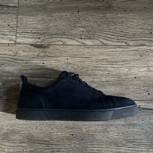 Christian Louboutin  - Säljer ett par stilrena svarta sneakers i mocka. De har en klassisk design med snörning och en bekväm passform. Perfekta för både vardag och festliga tillfällen. Skorna är i mycket bra skick och redo för nya äventyr! Box o dustbag med kommer!