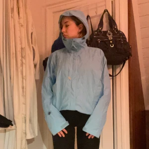 Ljusblå vindjacka från Columbia  - Säljer en ljusblå vindjacka i bra skick. Den har en praktisk huva och dragkedja framtill. Perfekt för vår och höst när det blåser lite extra. Jackan är långärmad och har en avslappnad passform. Perfekt för vardagsbruk eller promenader i naturen.