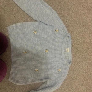 Blå Stickat tröja med blommor - Jag säljer en stickat blå tröja med blommor på. Den är super gullig och snygg. Den är 128-134cm för barn 8-9 år