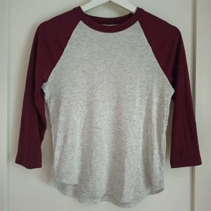 Grå och vinröd tröja från H&M - Säljer en snygg och bekväm grå tröja med vinröda ärmar från H&M. Tröjan har trekvartsärmar och är gjord av mjuk bomullsmix, perfekt för en avslappnad stil. Färgerna passar mycket bra under hösten och vintern💕