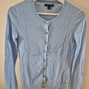 Kofta Tommy Hilfiger - Ljusblå kofta med guld färgad knappar från Tommy Hilfiger. Stechbar. Mjuk material. Använd några gånger. Storlek XS. 100% bomull. Lite nopprig. 