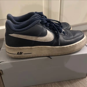 Svarta Nike Air Force sneakers - Säljer ett par blå Nike Air Force One sneakers. De har en klassisk design med vit sula och vit logga på sidan. Skorna är i använt  skick och  är fortfarande riktigt snygga och bekväma. 