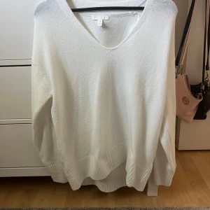 Vit tröja med v-ringning från H&M - Säljer en superfin vit tröja från H&M i storlek XS. Den har en snygg v-ringning och är perfekt för både vardag och fest. Tröjan är i bra skick och har ribbade detaljer vid ärmslut och nederkant. Passar perfekt till jeans eller kjol!