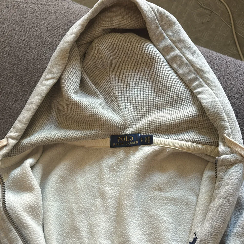 Säljer en supermysig grå zip hoodie från Polo Ralph Lauren. Den har en dragkedja framtill och en klassisk logga på bröstet. Perfekt för höst och vinter med sin mjuka och varma känsla. Den har långa ärmar och en praktisk huva med dragsko. . Tröjor & Koftor.