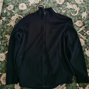 Hugo boss tröja med dragkedja - Riktigt fint tröja med dragkedja.  Ny pris:1799 kr.Det är ny skick. Längden: 67 cm  Breden: 56 cm 