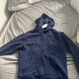 Blå Ralph lauren zip hoodie - Säljer nu min marinblåa Ralph lauren hoodie pga jag har växt ur den den är i fint skick ganska ny. Storlek 14-16 men passar också 13.