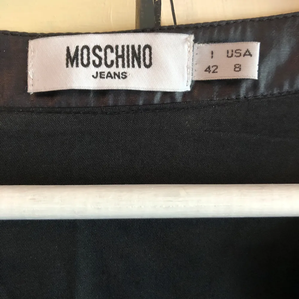 En svart tunika/klänning i från Moschino Jeans. Fint skick. Längd 90 cm Märkt strl I 42 och 8 USA. Klänningar.