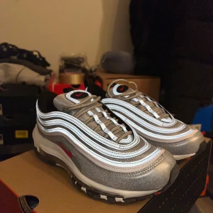 Nike Air Max 97 Silver - Säljer ett par helt nya (endast provade inomhus) Nike Air Max Silver 97 storlek 38 som jag köpte till min tjej men de passade tyvärr inte henne. Priset på skorna ligger på över 1800kr om ni kollar på internet mitt pris är endast 1000kr. 