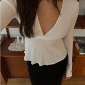 Vit blus med knyt i ryggen  - Säljer en stilren vit blus med långa ärmar och knytband i ryggen. Toppen har en v-ringad design och är tillverkad i ett lätt och bekvämt material. Använd 2 gånger, nypris 299kr💓💓